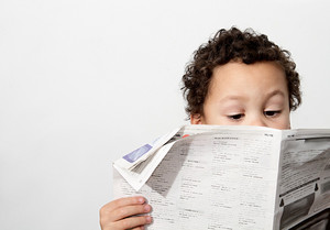 Little boy reading newspaper and smiling in the morning been educated with white background stock image and stock photo