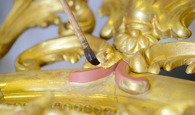 Closeup of paintbrush on gilt frame