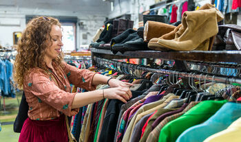 Woman browsing through vintage clothing in a Thrift Store.