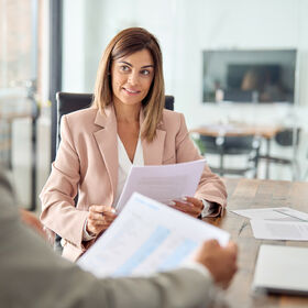 Mature business woman manager discussing documents at office meeting.